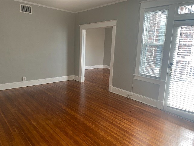 an empty living room with wood floors and a window